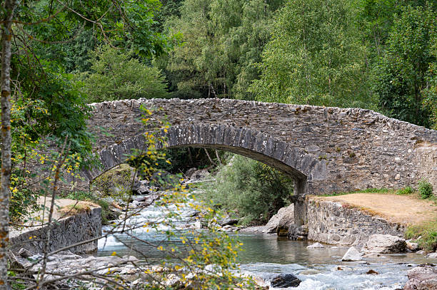 istock Scenic view of Pyrenees stone bridge over Gavarnie stream at dawn, surrounded by lush greenery and majestic mountains 2232131821