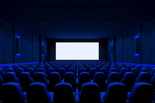 istock Interior of empty cinema with blank white screen and clean blue-lit seating viewed from the back row towards the front wall. 3D Rendering 2232133953