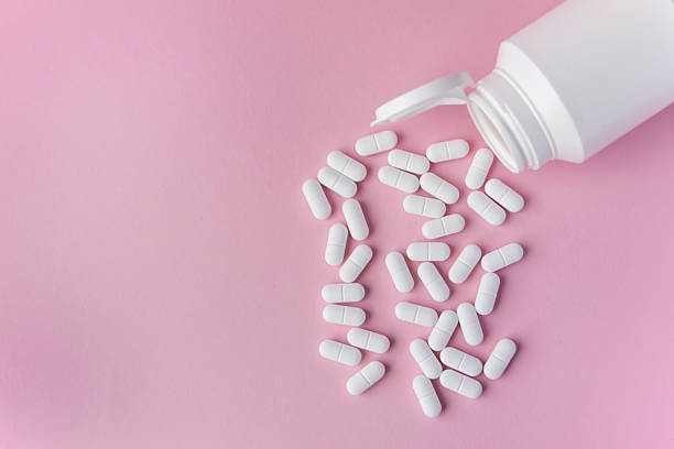 istock White pills on the pink background with place for text. 2232135445