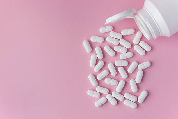 istock White tabletts or pills on the pink background with place for text. 2232135468