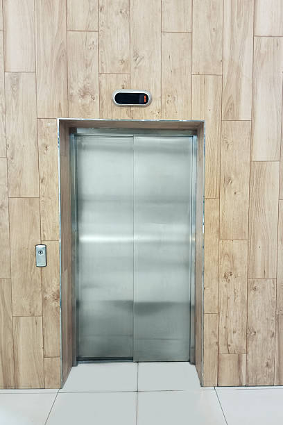 istock Closed metal elevator doors against a wooden wall. 2232135493