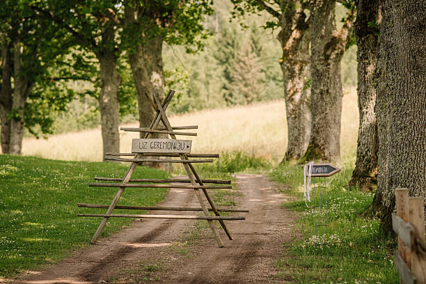 istock Rustic wooden signs on a forest path direct guests to a ceremony, likely a wedding, with text in Latvian (UZ CEREMONIJU) and nature surrounding the route. 2232135692