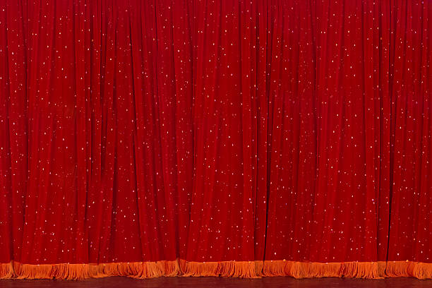 A red curtain with stars on it. The curtain is hanging on a stage