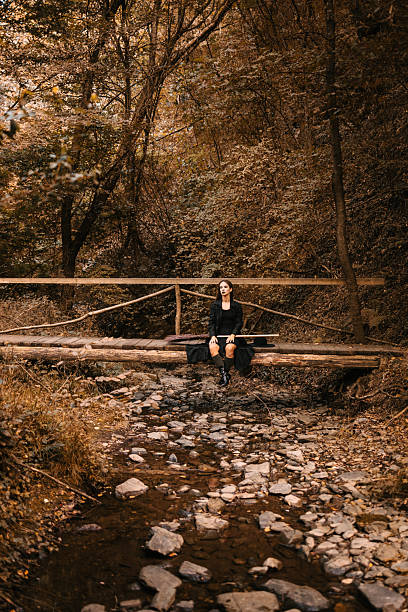 istock Sad witch sitting on wooden bridge with broom and hat during Halloween 2232136730