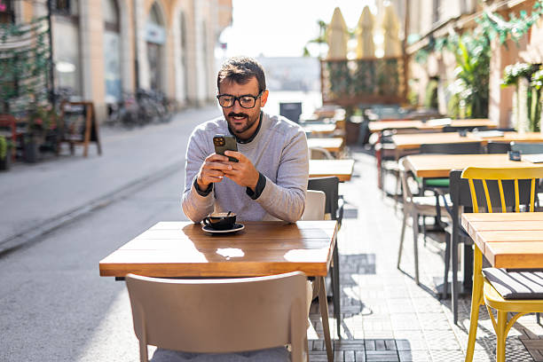 istock Young businessman using smartphone and drinking coffee at outdoor cafe 2232139810