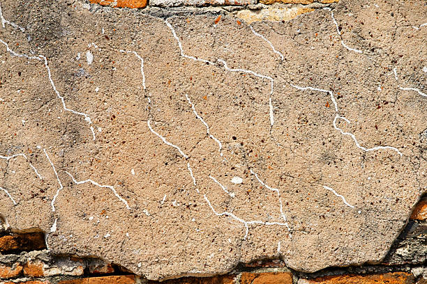 An old red brick wall exhibits a prominent crack running from top to bottom