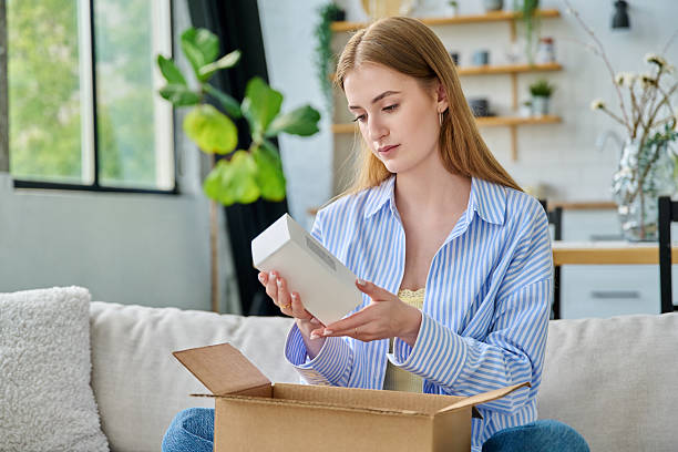 istock Young happy woman unpacking cardboard box with online order 2232142436
