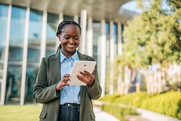 istock Smiling businesswoman using digital tablet outside office building 2232142444