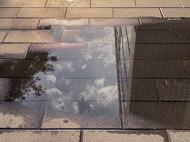High angle close-up view of the reflection of the sky over water on the sidewalk