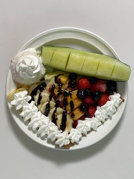 Delicious ice cream-filled crepes, drizzled with chocolate sauce and topped with fresh fruits. Perfect for dessert photography, showcasing the delightful combination of flavors and texture