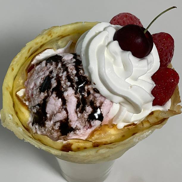 Delicious ice cream-filled crepes, drizzled with chocolate sauce and topped with fresh fruits. Perfect for dessert photography, showcasing the delightful combination of flavors and texture