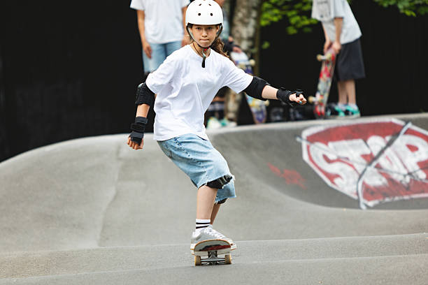 Schoolage girl skateboarding on pump track at skateboard park