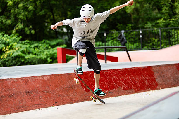 School age boy skateboarding and making ollie