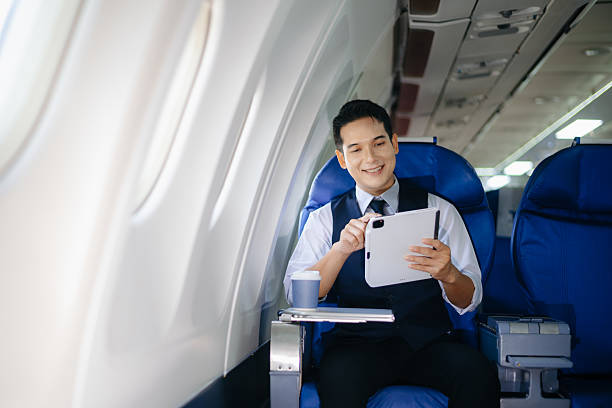 Young businessman working on a tablet while enjoying coffee in first class. Perfect image for travel, corporate lifestyle, and modern technology themes.