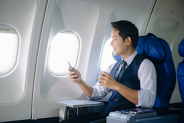 Young businessman working on a tablet while enjoying coffee in first class. Perfect image for travel, corporate lifestyle, and modern technology themes.