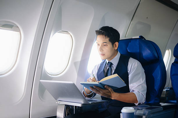 istock Businessman working on a laptop with documents during a first-class flight. Perfect for themes of productivity, corporate travel, and global business success. 2232158665