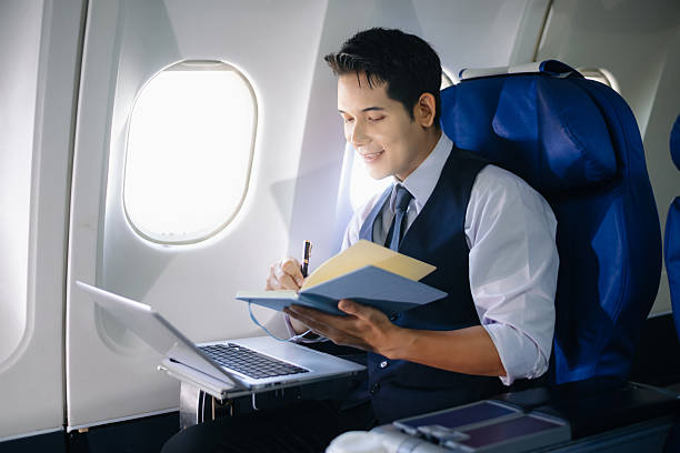 istock Businessman working on a laptop with documents during a first-class flight. Perfect for themes of productivity, corporate travel, and global business success. 2232158677