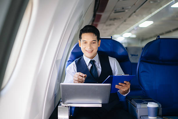 istock Businessman working on a laptop with documents during a first-class flight. Perfect for themes of productivity, corporate travel, and global business success. 2232158680