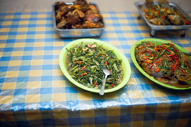 A variety of prepared dishes featuring vegetables and fish placed on a brightly colored tablecloth