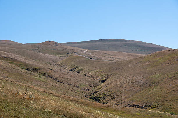 istock Vehicles on Remote Road in Rugged Highland Terrain and Dry Farming Fields 2232160509