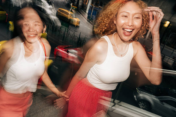 Two young women laughing in city with motion blur