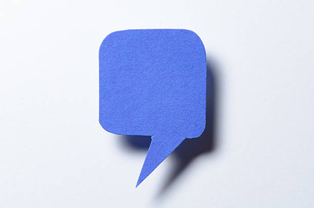 Blue blank cut out paper speech bubble with drop shadow and copy space for text on white background, close-up flat lay top view conceptual backdrop