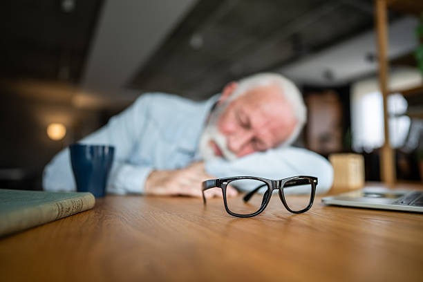 istock Senior man sleeping at desk after working on laptop 2232169495