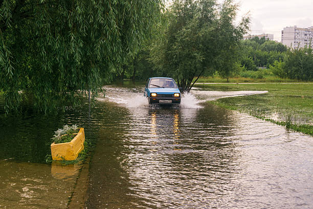 Moscow, Russia - July 23, 2025: small car crossing a puddle in a flooded park on a rainy day
