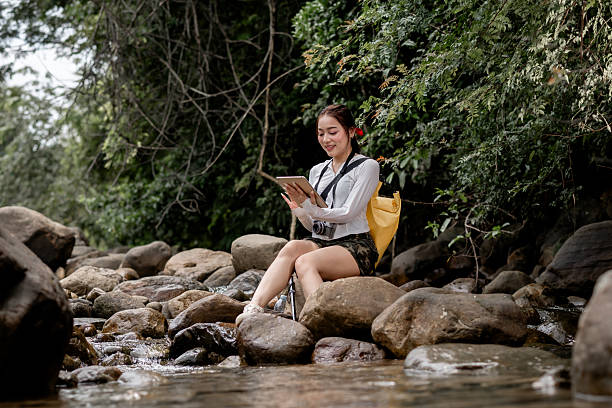 istock Woman is exploring nature enjoying holding and looking at a tablet, possibly using navigation, reading, or recording journey representing  nature and modern technology. 2232170425