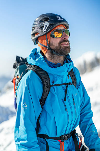 istock Experienced Male Mountaineer in Bright Sunlight on Snowy Mountain Summit 2232171930
