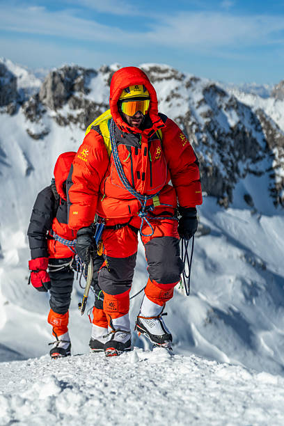 istock Professional Mountain Climbers Roped Together Ascending Snowy Alpine Peak In Bright Safety Gear 2232172009