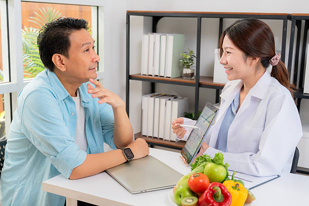 istock Asian nutritionist using tablet to explaining personalized meal plan with AI to patient during healthcare consultation, healthy lifestyle, woman dietitian showing nutrition plan with AI on tablet. 2232172757