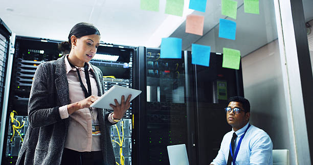 istock Woman, tablet and planning with man in server room, discussion and notes for IT solution at company. People, cybersecurity and team with tech, app and information technology for diagnostics test 2232174335