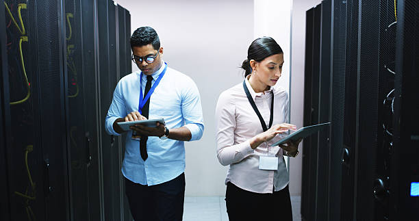 istock Man, woman and tablet in server room, inspection and checklist for IT solution at company. People, cybersecurity team and hardware with tech, app and information technology for system maintenance 2232174337
