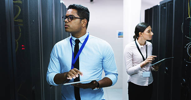 istock Man, woman and tablet in server room, storage and checklist on app for IT solution at company. People, cybersecurity team and system assessment with tech, review and information technology at agency 2232174347