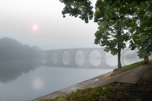 On a winter’s day, Hexham Bridge stretches across the River South Tyne, linking the town with the North Tyne valley and providing the main route to the A69 bypass. Trees line the riverbank, framing views of the bridge and the nearby weir, while a soft veil of mist drifts through the scene, adding a quiet, atmospheric charm.