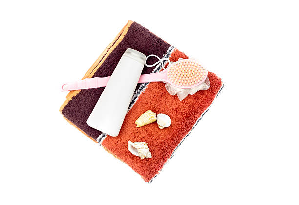 Two modern, new towels, shampoo and a washcloth with a handle on white background close-up