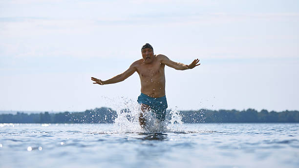 istock Older man running into cold water with surprised facial expression 2232176147