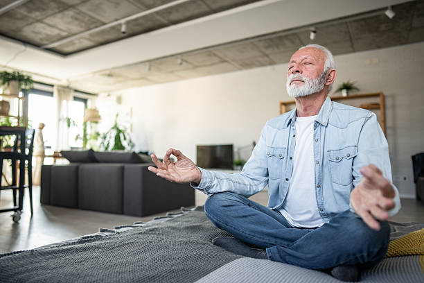 istock Senior man meditating in lotus position at home 2232176349