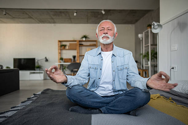 istock Senior man meditating in lotus position on bed at home 2232176737