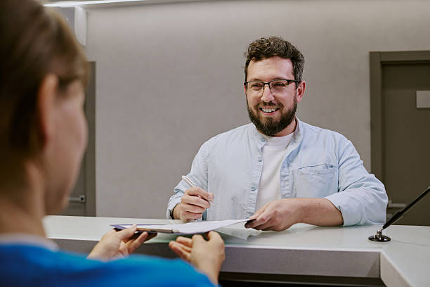 Caucasian Young Adult Man Smiling While Signing Documents at Reception Desk