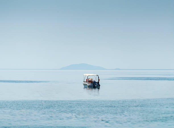 Sitting in traditional red and blue wooden boat sailing on Flores island, Indonesia during tropical rain