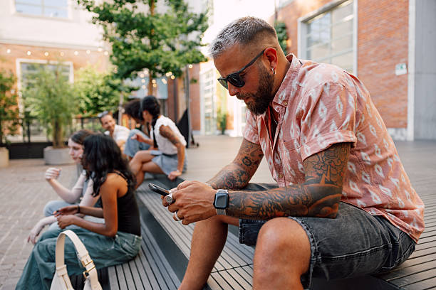 Man texting on mobile phone sitting on steps outdoors.