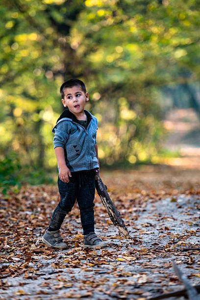 istock Curious child exploring nature holding stick in autumn forest 2232189248