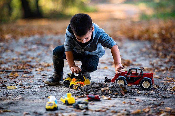 istock Young child playing with toy trucks in autumn forest 2232189387
