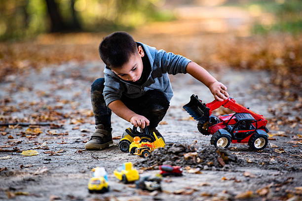 istock Young boy playing with toy trucks in a park during autumn 2232189530