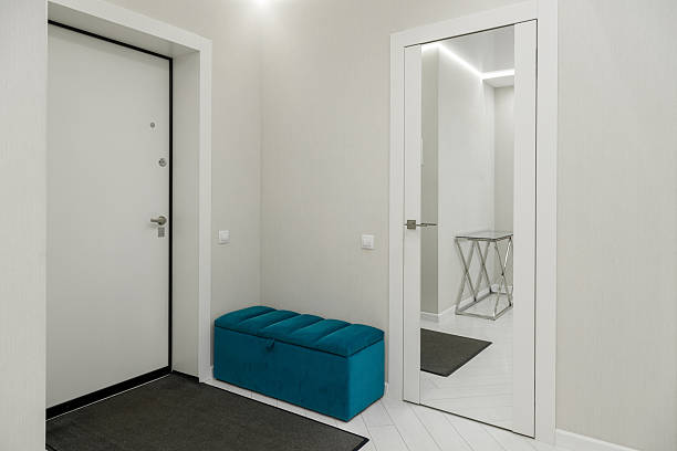 A contemporary entryway featuring a sleek mirror, a striped teal bench, and a minimalist design that enhances the aesthetic appeal of any home.