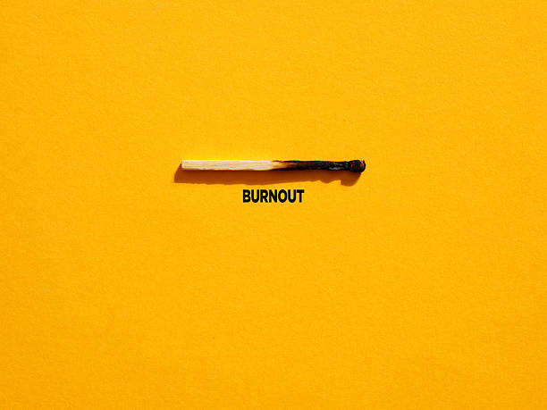 Burnt match on a yellow background with the word burnout written below representing the concept of professional burnout syndrome