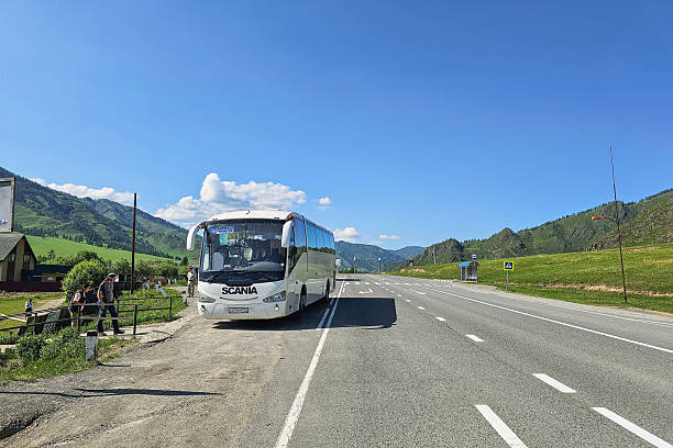 Barnaul, Russia - June 07, 2025: Regular white bus from Barnaul stopped at a stop in a remote Altai village on the highway. Transportation concept, city bus.