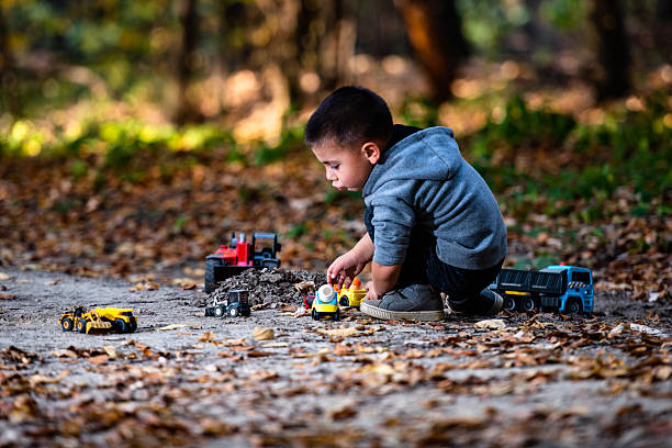 istock Young child playing with toy trucks in autumn forest 2232190990